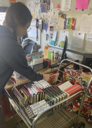 Claire White (‘23) pulls “The Catcher in the Rye” by J. D. Salinger from the array of banned books in Mrs. Houseknecht’s room. Salinger’s novel was removed from curriculum in Summerville, SC in 2001 due to parent complaints about the "filthy, filthy book." 